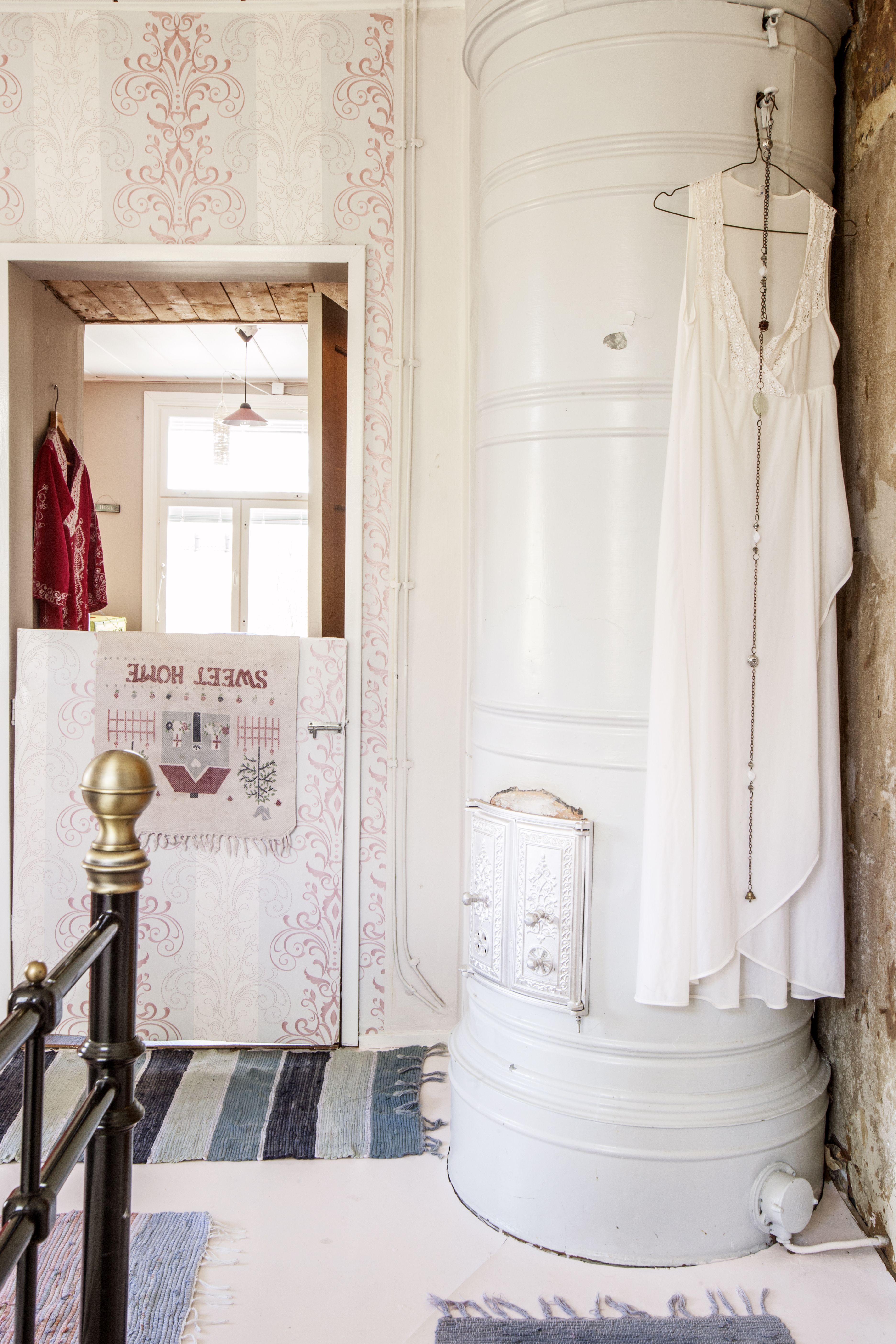 Vanhat pönttöuunit tuovat lämmön taloon. Koiria varten rakennettu portti on päällystetty samalla tapetilla kuin seinät.