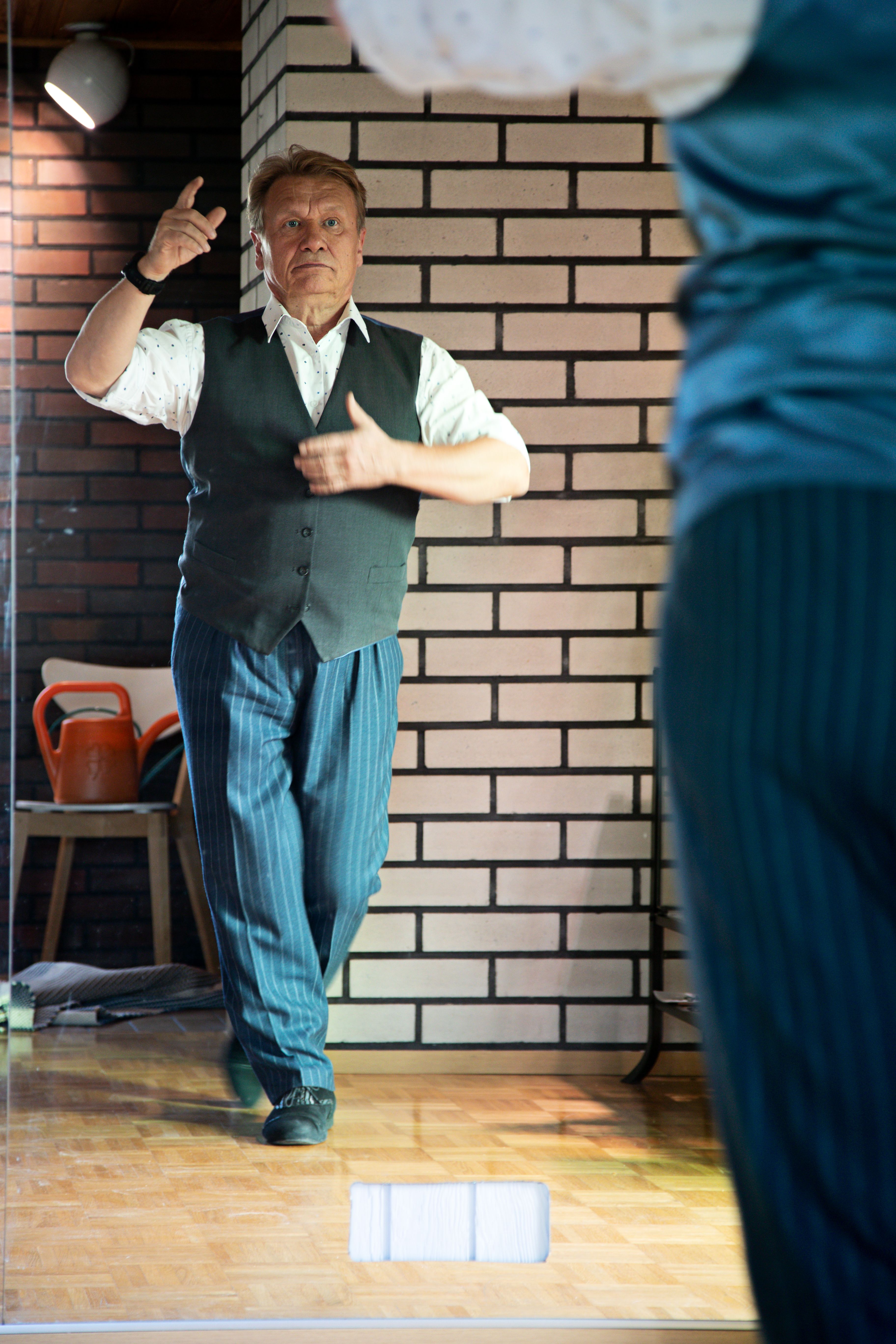 Pertti harjoittelee tanssia olohuoneen ison peilin edessä.