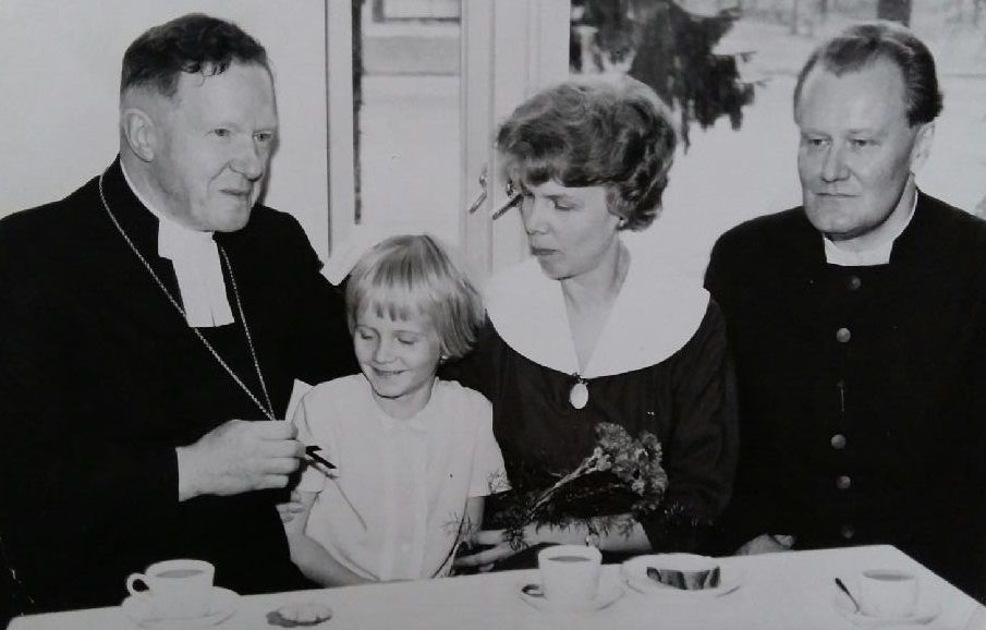 Juhlan hetki, kun Martti Nortia on asetettu papiksi Lahdessa. Kahvipöydän ääressä myös piispa Eelis Gulin (vas.), jonka ristiä Miitta tutkailee. "Olimme juuri muuttaneet Kiteeltä Lahteen. Minusta oli hienoa muuttaa kaupunkiin, vaikka olin hyvin viihtynyt Kiteellä. Äiti asui taas kanssamme. Hänestä tuli perheterapeutti."