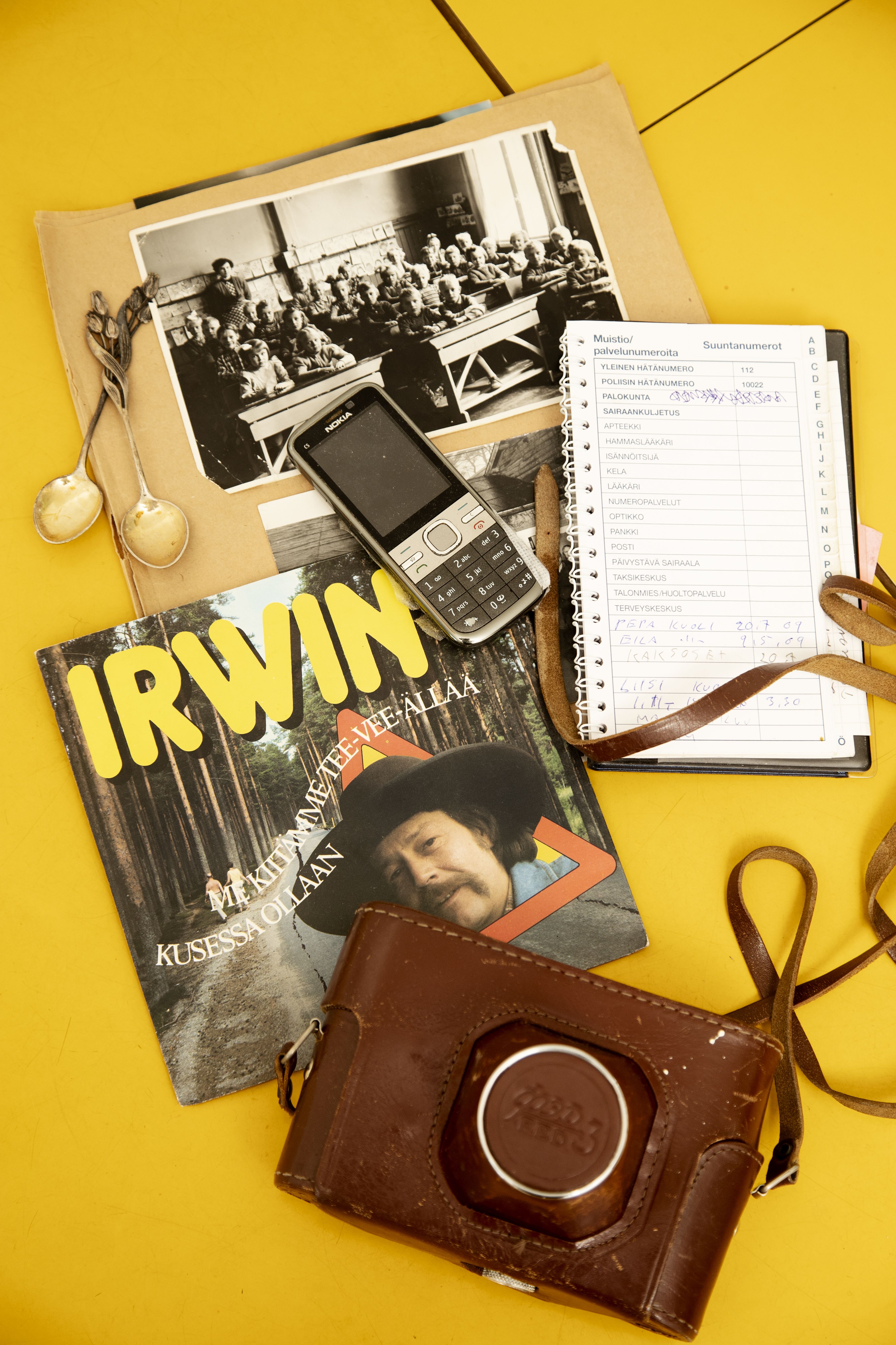 Isän perintöä: vanha koulukuva, lusikoita, muutama vinyylilevy, kamera, puhelin ja puhelinmuistio.