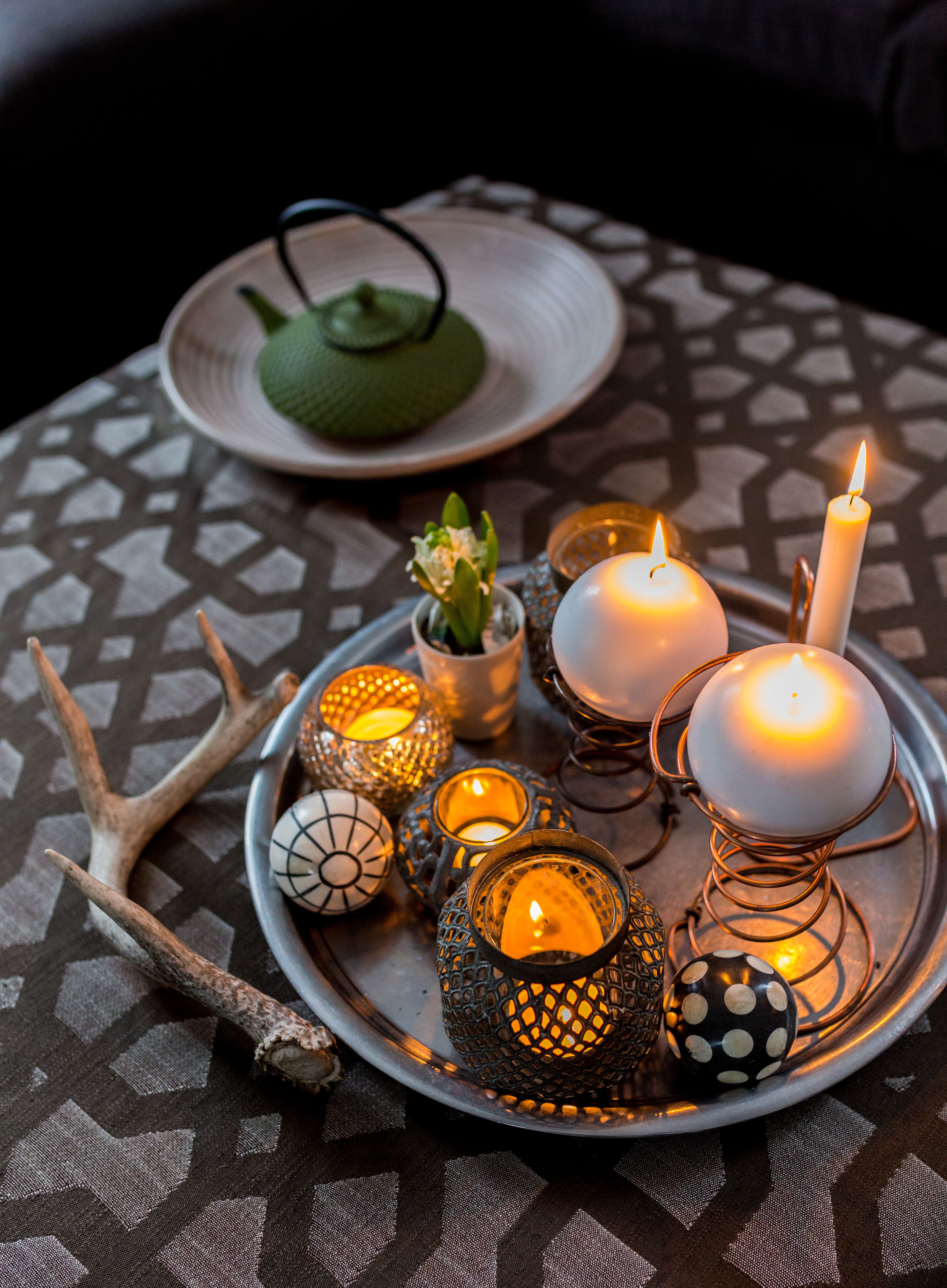 Tarjotin kokoaa lyhdyt ja koristeet asetelmaksi. Vieterikynttilänjalat ovat vanhan sohvan jousia.