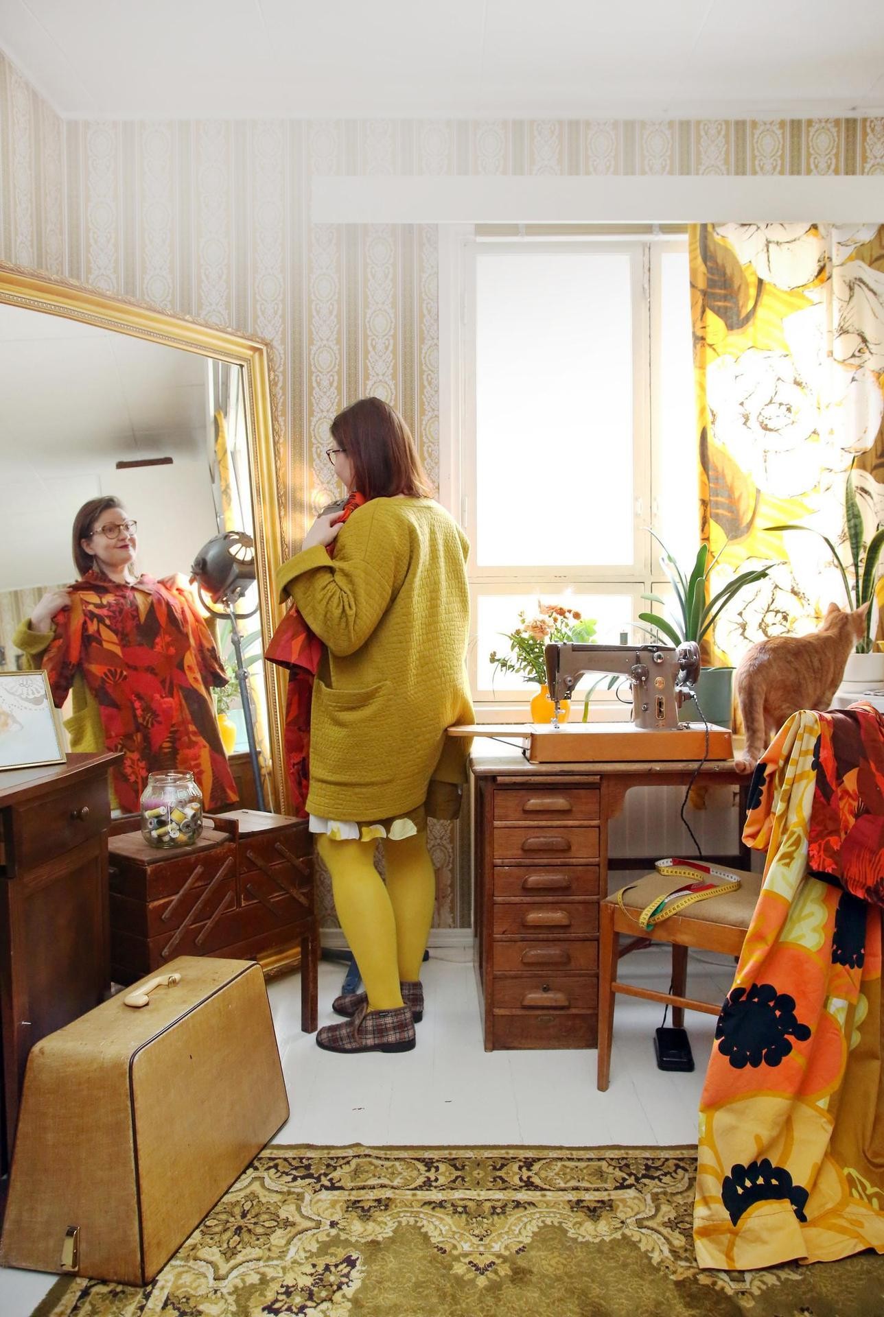 Peilistä näkyvä mekko on Marjatan tyttären Katariina Metsovaaran suunnittelemaa Tapiola-kangasta. Verhot ovat Valkeat Ruusut -kuosia ja tuolilla on Anemona-kangasta.