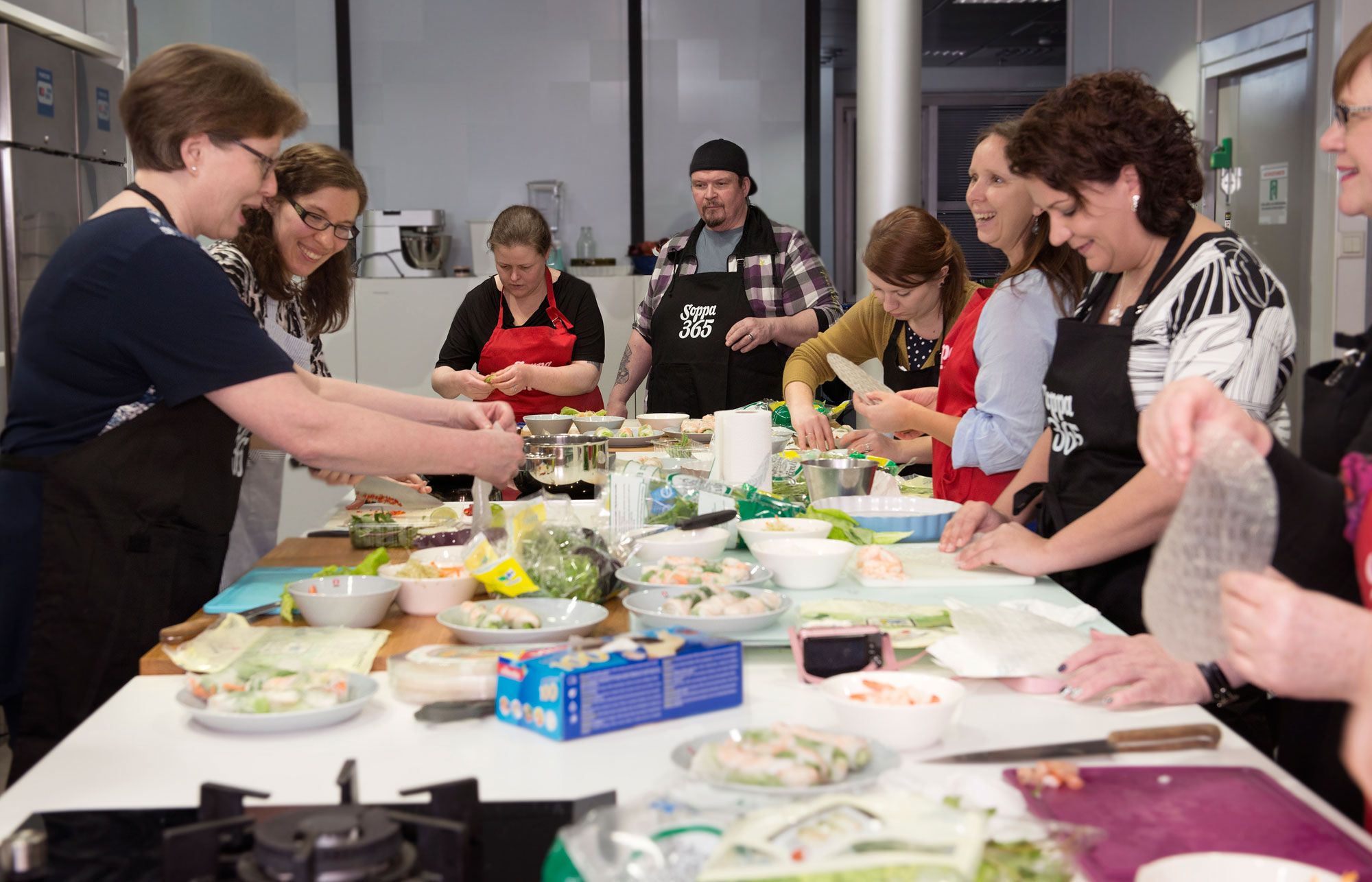 Riikka Kaila (toinen vasemmalta) näyttää jokaiselle erikseen, miten riisipaperia on helpoin käsitellä.