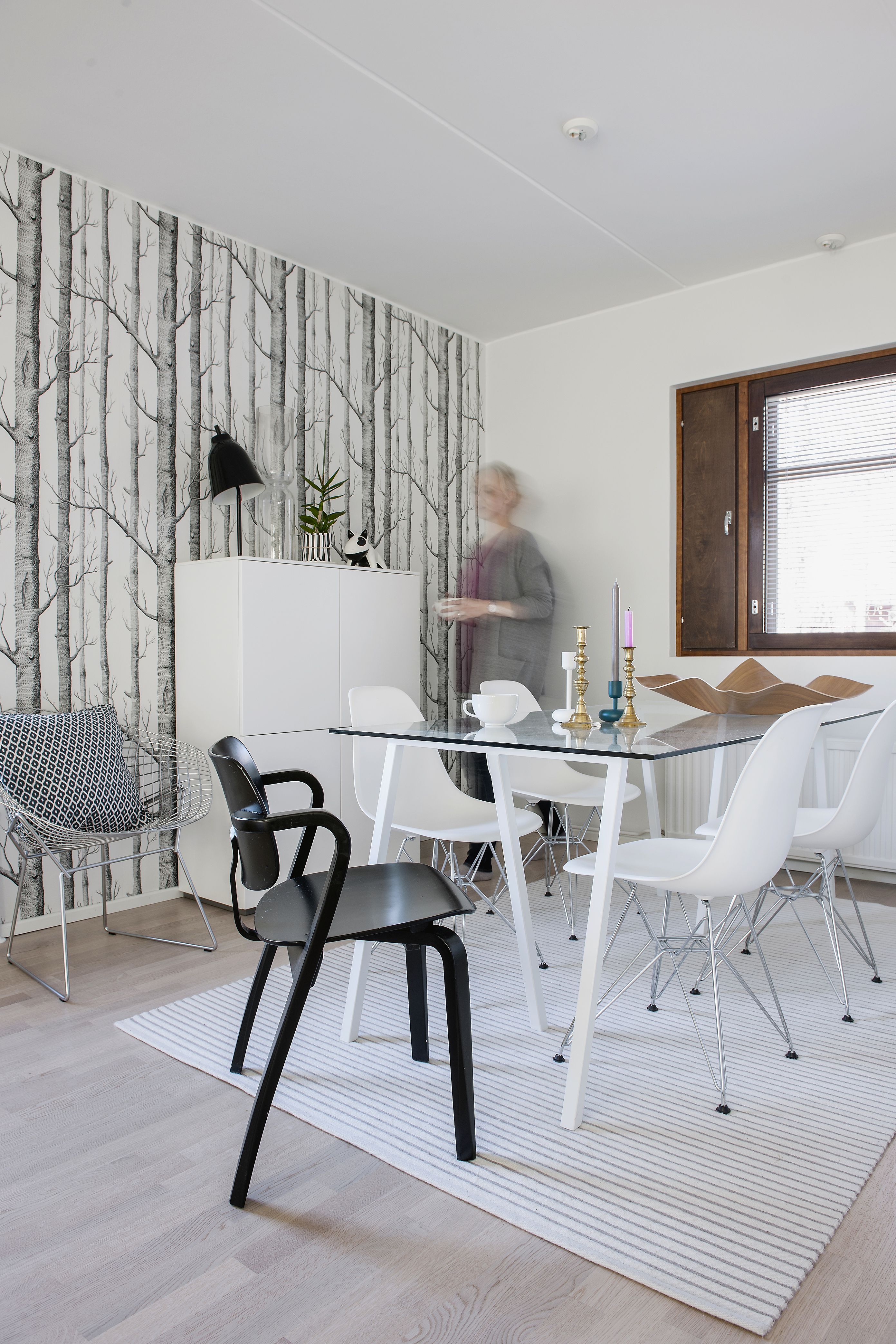 Ruokapöytä syntyi Hayn pukkijalkojen päälle asetetusta lasilevystä. Kevyen pöydän seuraan sopivat hyvin Vitran metallijalkaiset DSR-tuolit. Mustavalkoisuus tekee tilasta raikkaan graafisen. Nahkainen koira kaapin päällä on Vinkel Homesista.
