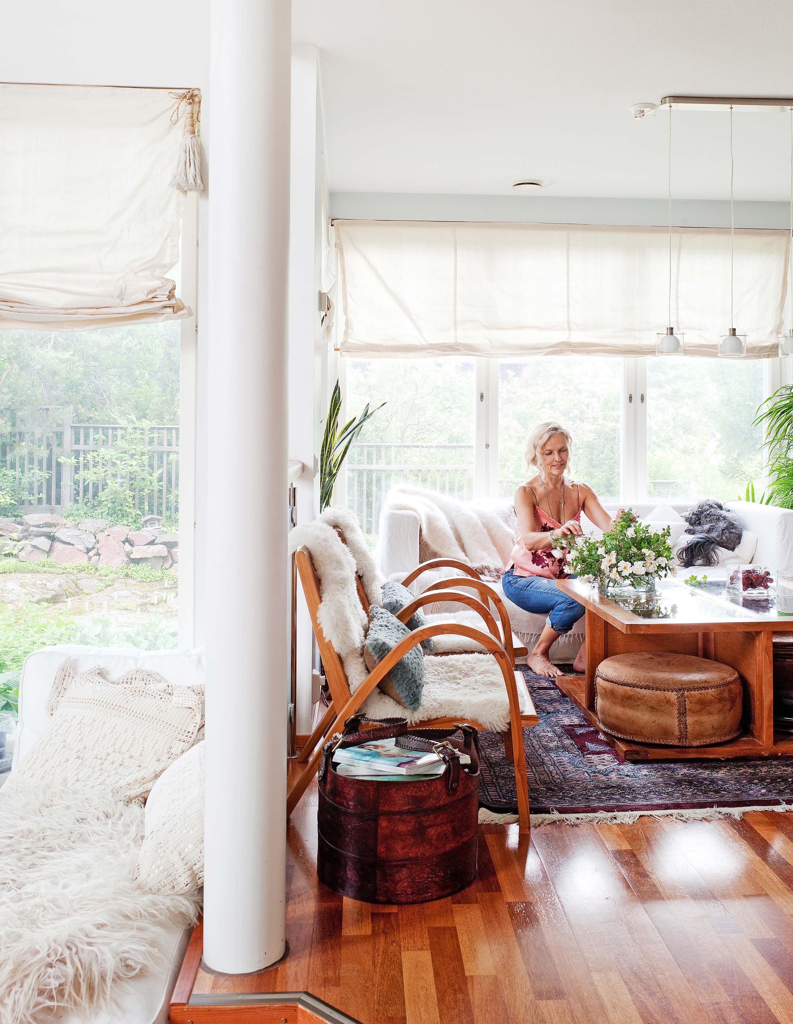 Heidi muutti keittiön viereisen tilan oleskelutilaksi. Perheen vanhin koira Rooti loikoo sohvalla, kun Heidi asettelee kukkia. kalusteet ovat pääosin Aasiasta. Kaunis, nahkainen lehtikori löytyi Ruotsista. 