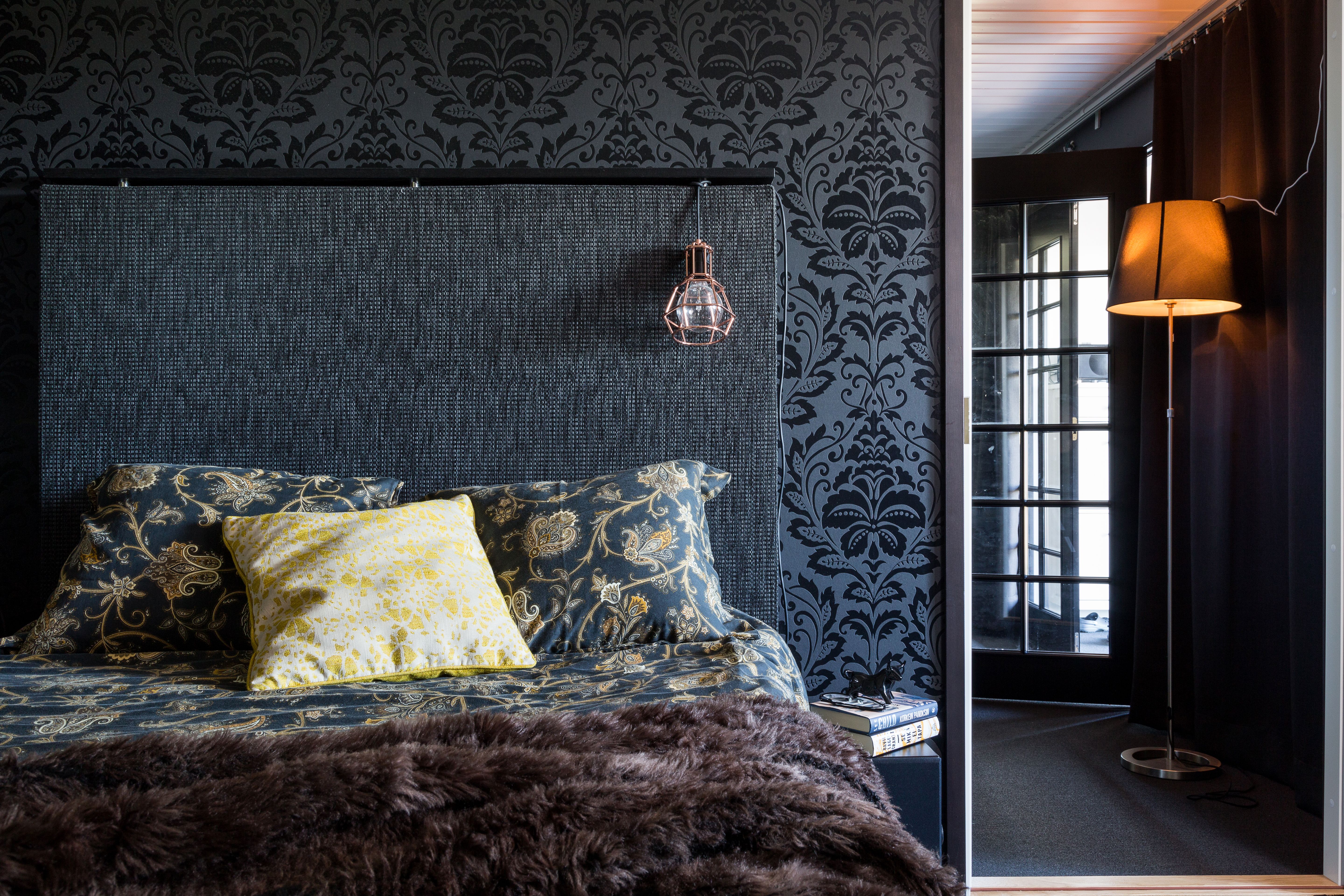 Musta sängynpääty sulautuu väritykselläään seinään. Tummat sävyt rauhoittavat. Kuva Tiiu Kaitalo