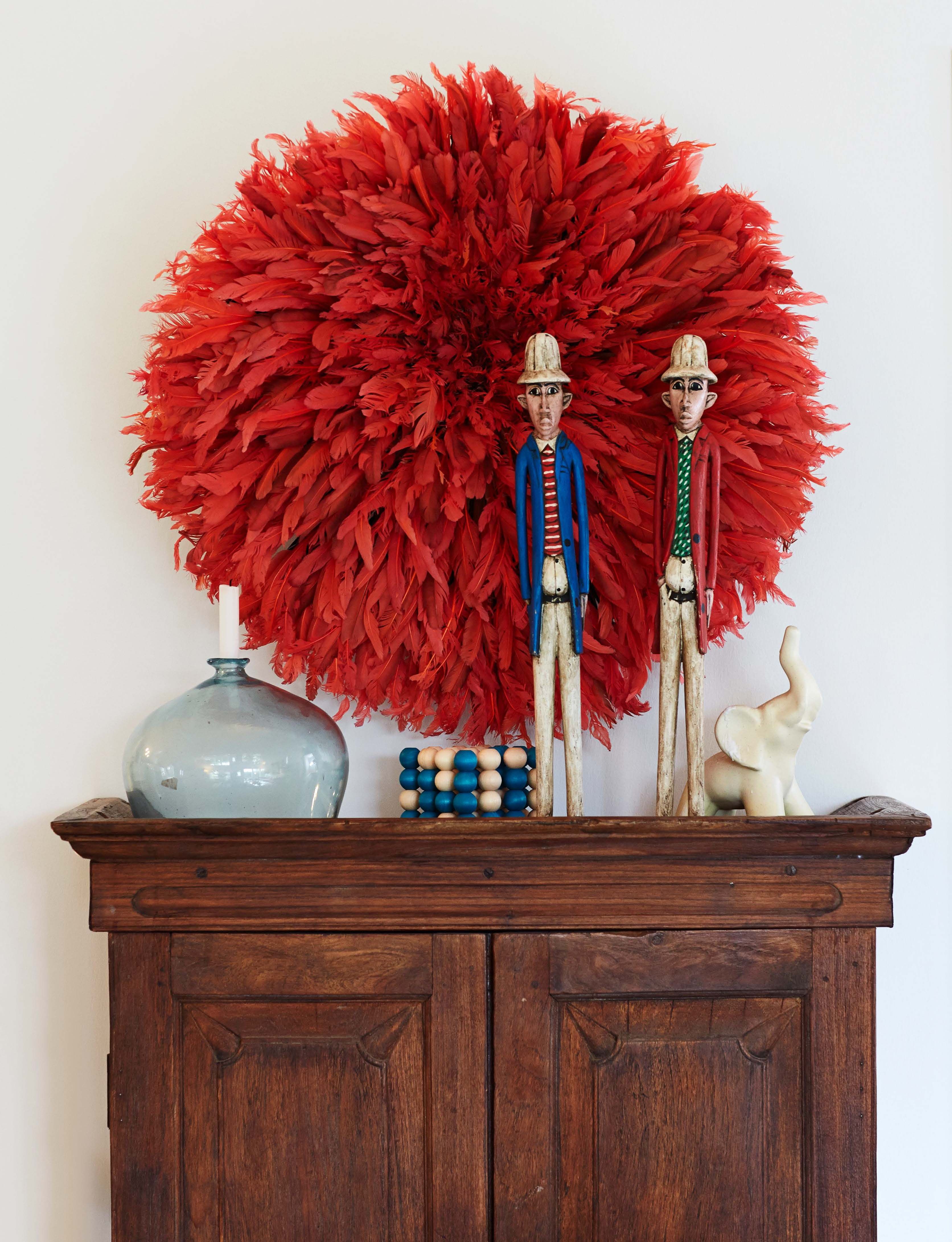 Muhkea sulkakoriste on kamerunilainen Juju-hattu, seremoniapäähine. Puunuket ovat kenialaista käsityötä. Ne viihtyvät Kerttu Suvanto-Vaajakallion suunnitteleman valkoisen norsun kaverina.