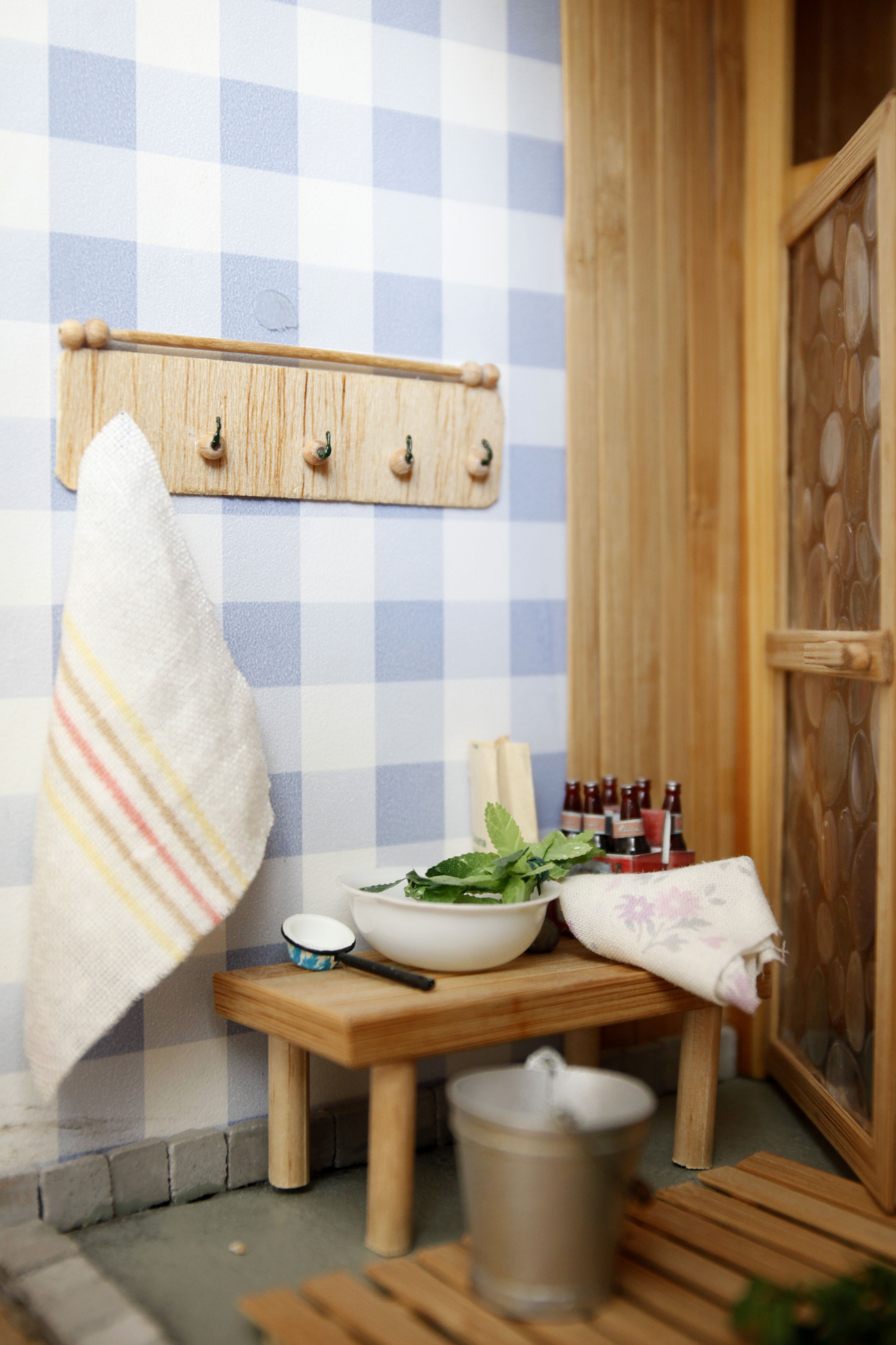 Nukkekaapin saunaosaston sopivan karkeat pellavapyyhkeet houkuttavat kylpemään. Saunajuomatkin ovat valmiina korkattaviksi.