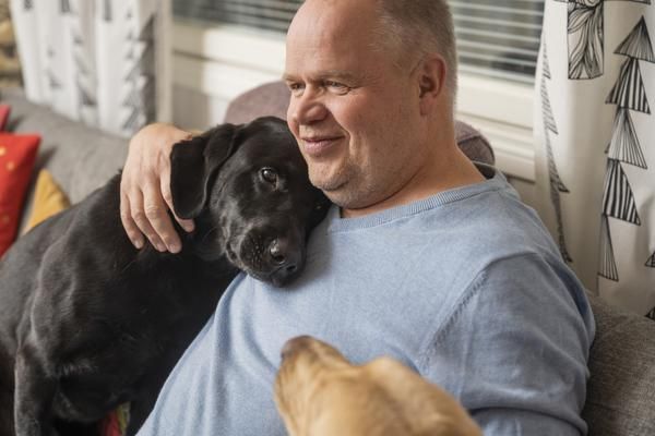 Mika ja Pepi ovat työkavereita mutta myös toisilleen rakkaita perheenjäseniä. Mikan kainaloon kurkottelee myös Pepin seuraaja, yksivuotias labradorinnoutaja Valpas.