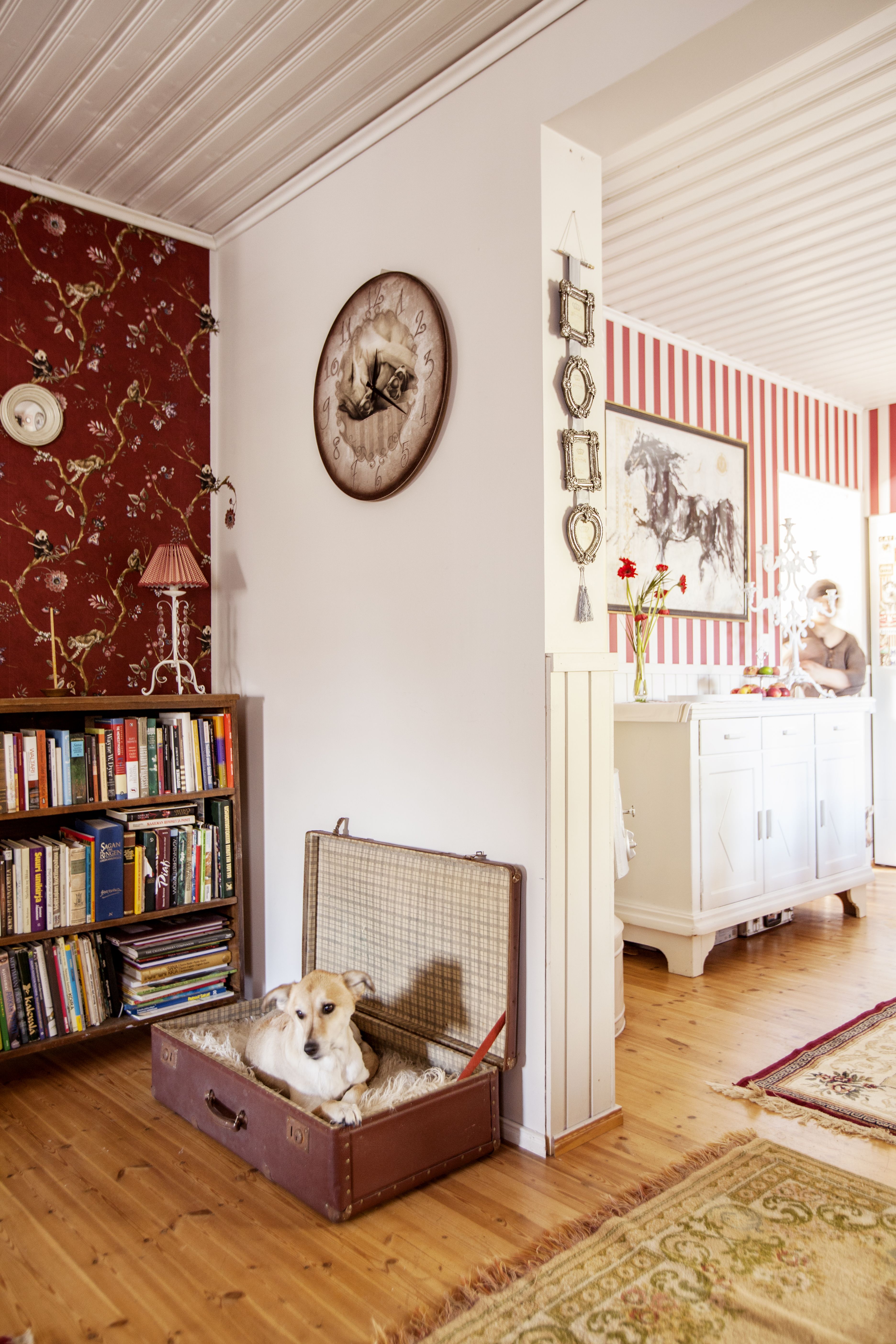 Olohuoneen ja ruokailutilan ovella on Tellu-koiran lepopaikka, vanha matkalaukku. Seinäkello on Millan maalaama.