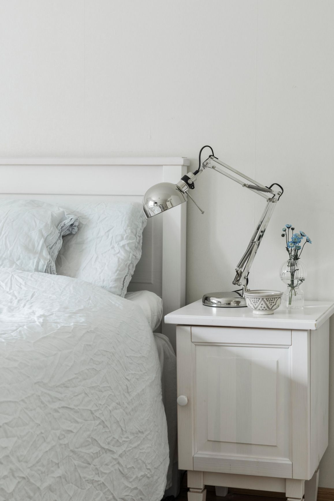 Makuuhuoneessa tavaran määrä on minimoitu. Siniset kukat maljakossa luovat rauhallista tunnelmaa.