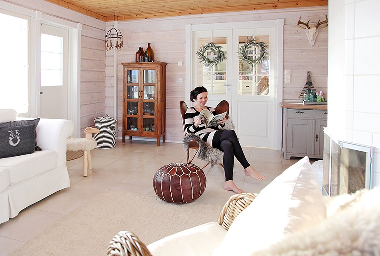 Olohuoneen lepakkotuoli on Tarjan lempipaikka. Hän maalasi edellisen talon kellarista löytyneen kirkkaanpunaisen patakaapin uuden kodin sävyihin sopivaksi. Paikallinen metsästäjä lahjoitti peuransarvet.