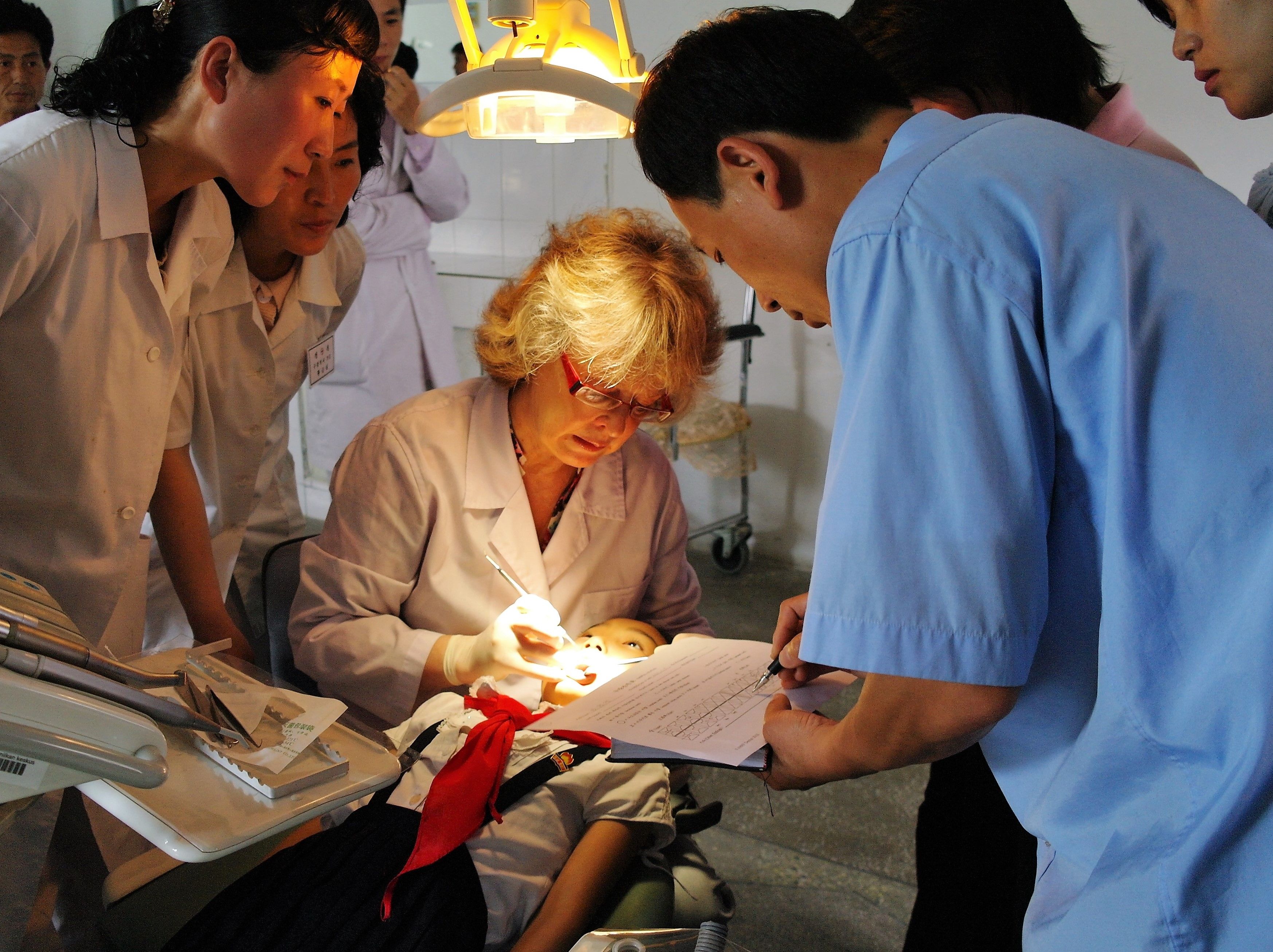 Pohjois-korealaiset hammaslääkärit katsovat, kuinka tutkin lapsen suun.
