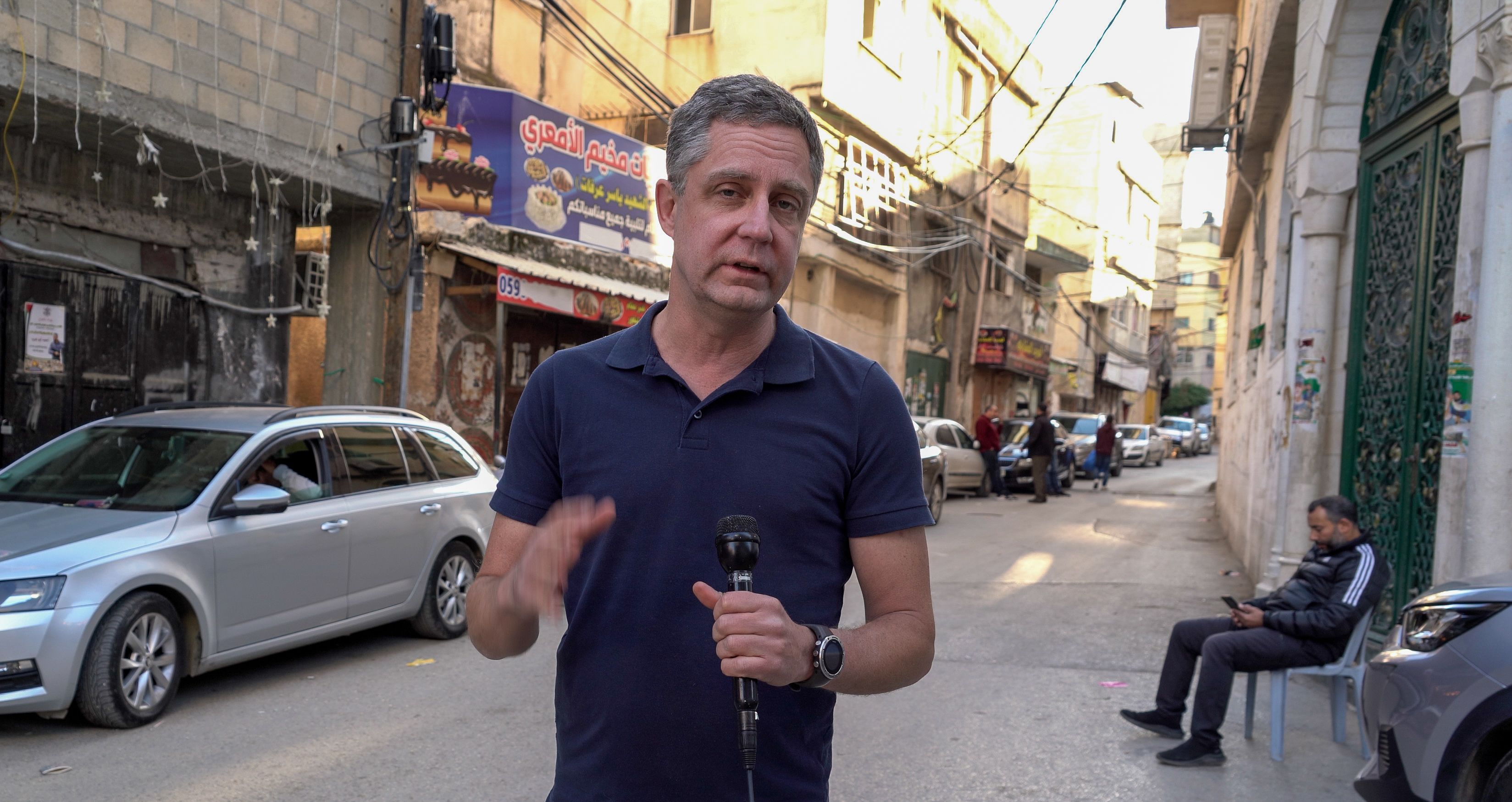 <macro_up> Antti raportoi tv-uutisiin Amarin pakolaisleiristä Länsirannalta. ”Matkalla tärkeintä on jaksaa jatkaa työtä, eikä ahdistukselle saa antaa valtaa. Myöhemmin ehdin käsitellä asioita enemmän.” 