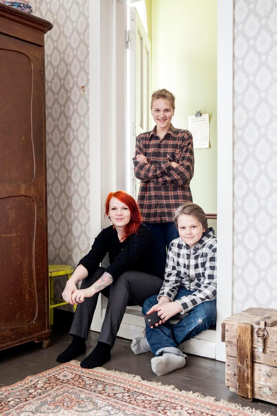 Jenni, Micael ja Cristofer poseeraavat vanhempien makuuhuoneen ovella. Huoneen kaunista, vanhaa tapettia ei tee mieli vaihtaa.