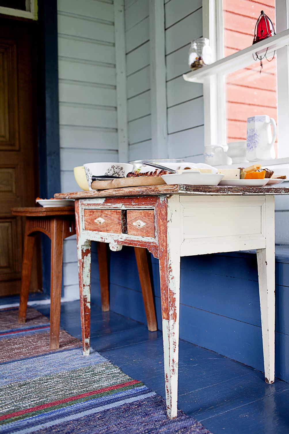 Siniseksi maalatulle kuistille on mukava kattaa pöytä valmiiksi ennen sukulaisten tapaamista.