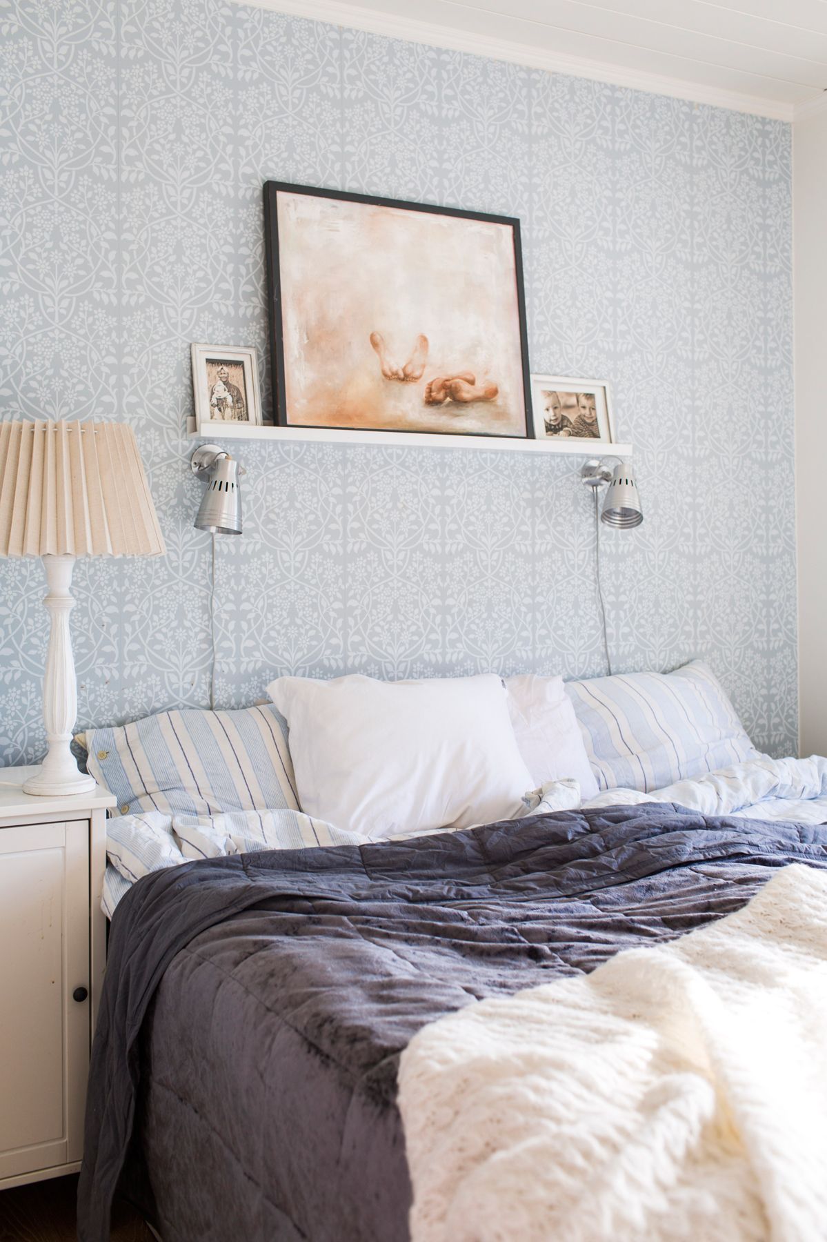 Makuuhuoneen värit valikoituivat Tapettitalon siniharmaan Lukko-tapetin mukaan. Hyllyllä on Johannan maalaus ja kuvia rakkaimmista.