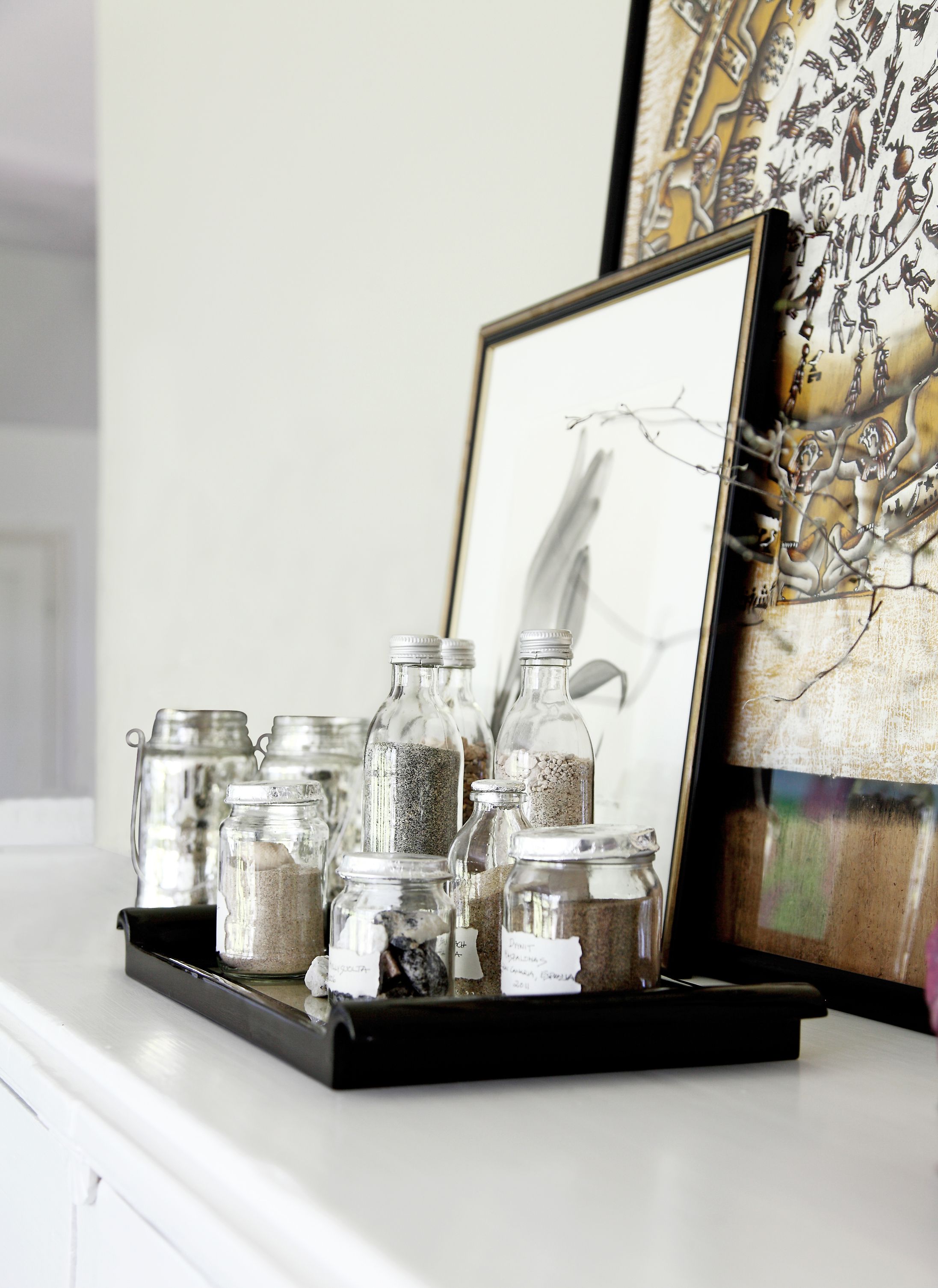 Pieniin lasipulloihin ja -purkkeihin on kerätty hiekkaa matkoilta lähelle ja kauas.