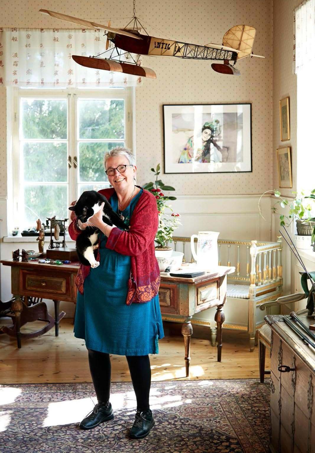 Li ja Iiris-kissa kotona kansakoulun suuressa salissa. Maalauksessa seinällä on tytär Lotta.