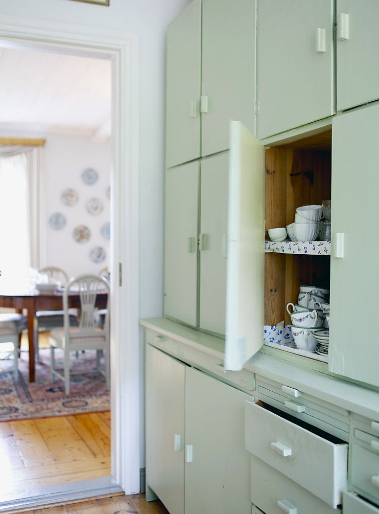 Mintunvihreät kaapit keittiön ja ruokasalin välisessä käytävässä ovat täynnä sinistä ja valkoista posliinia.
