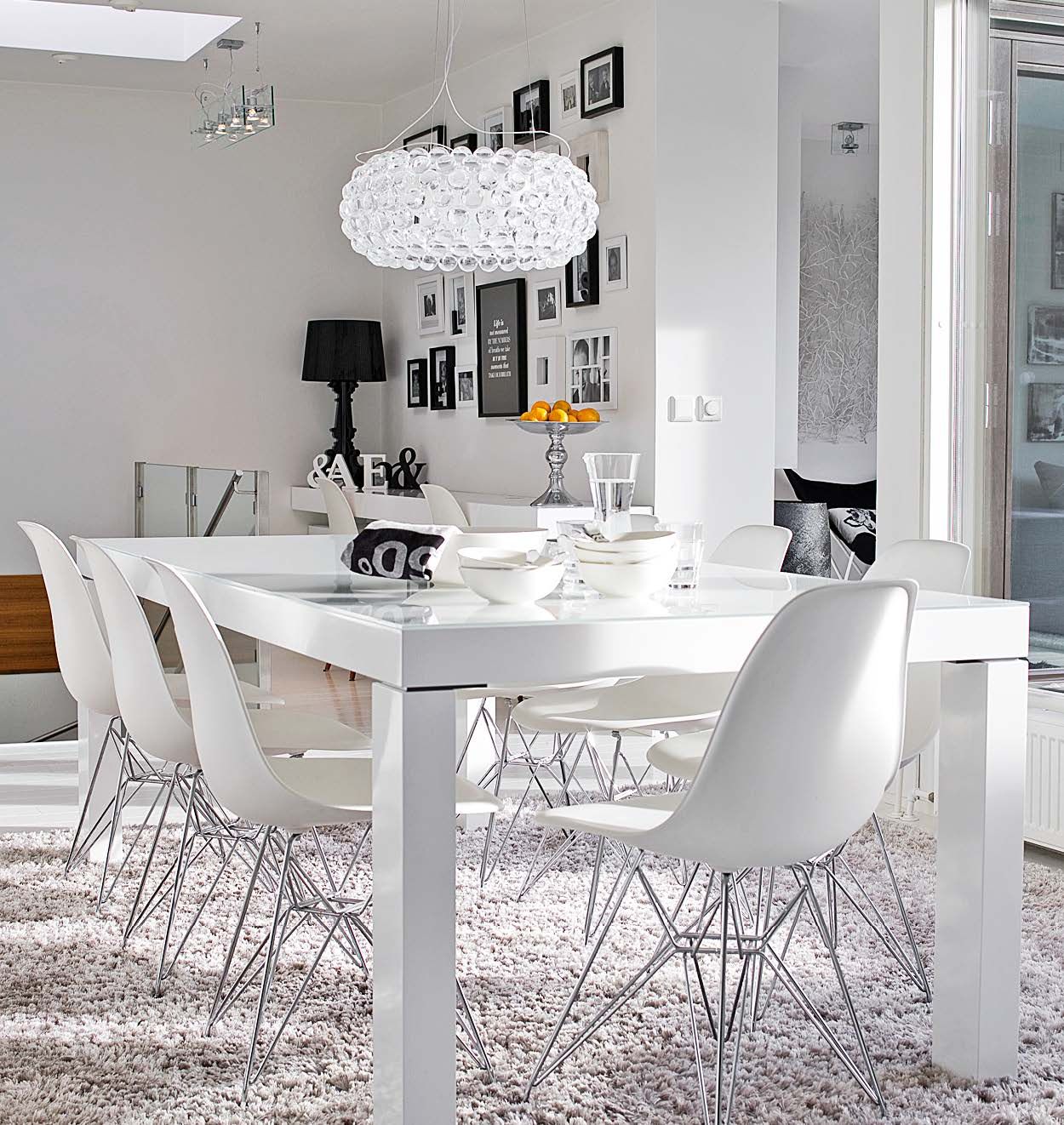 Selkeä ruokailutila kylpee luonnonvalossa. Harmaa nukkamatto suorastaan imaisee leivänmurut sisäänsä. ”Siksi se on yllättävän hyvä ratkaisu ruokapöydän alla”, Henriikka sanoo.