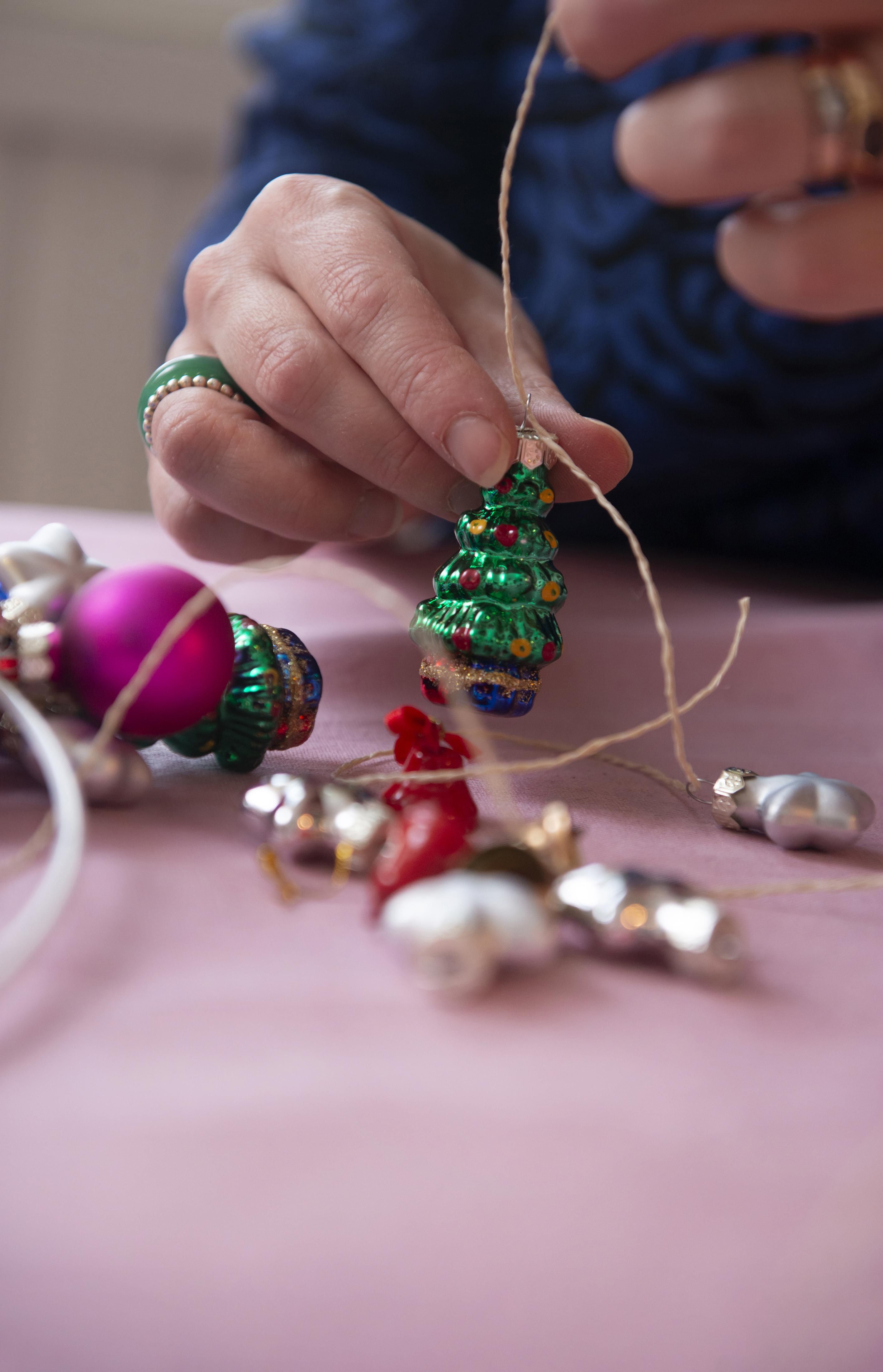 Kaikki kotoa löytyvät joulupallot ja muut koristeet yhdistyvät Niinan käsissä pallokranssiksi. Hän pujottaa koristeet naruun ja kietoo sen metallirenkaan ympärille. Tuloksena on ”vähän överi” kranssi, joka odottaa ripustamistaan oveen.