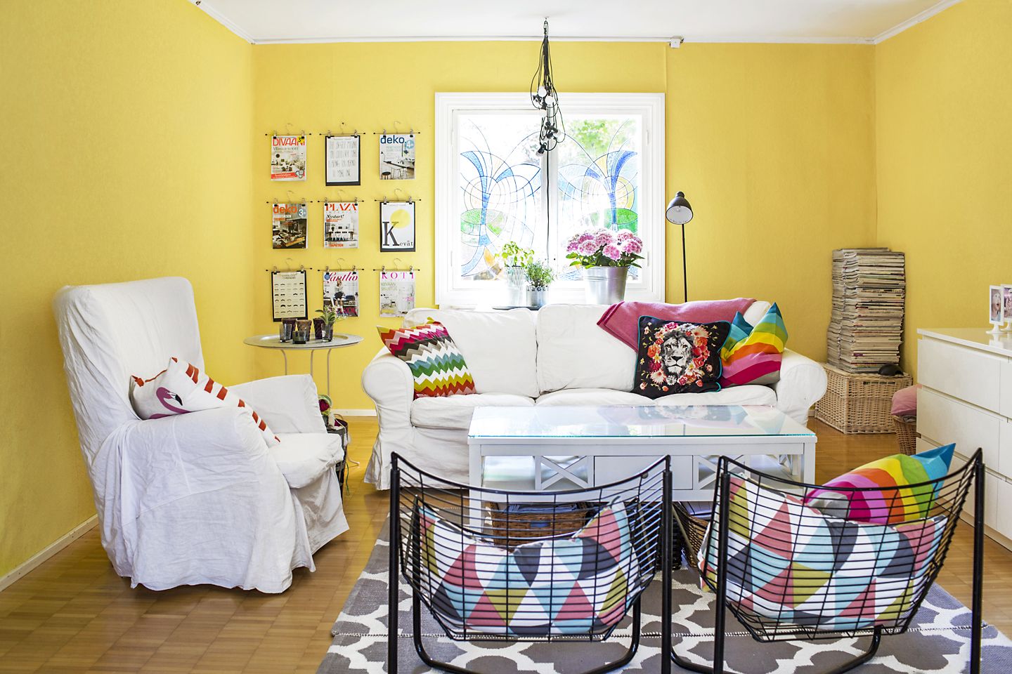 Keltainen seinämaali tekee kodin aurinkoiseksi. Entinen asukas, lasitaiteilija, teki ikkunoihin upeat koristeet. Housuhenkareihin ripustetut sisustuslehdet ovat kuin tauluja. 