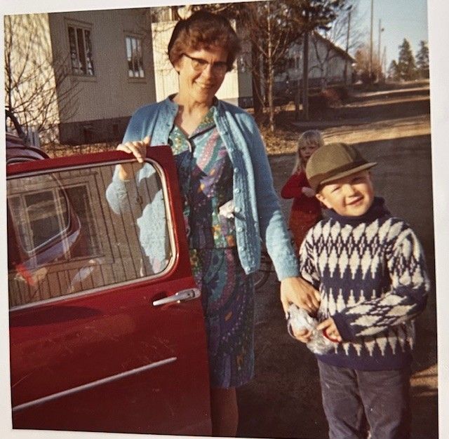 <macro_left> Kummitäti Aune Ihalainen Timon kanssa Metsäkadulla 1970-luvun alussa. Aune ja Timo tekivät punaisella Fiatilla monta yhteistä matkaa.