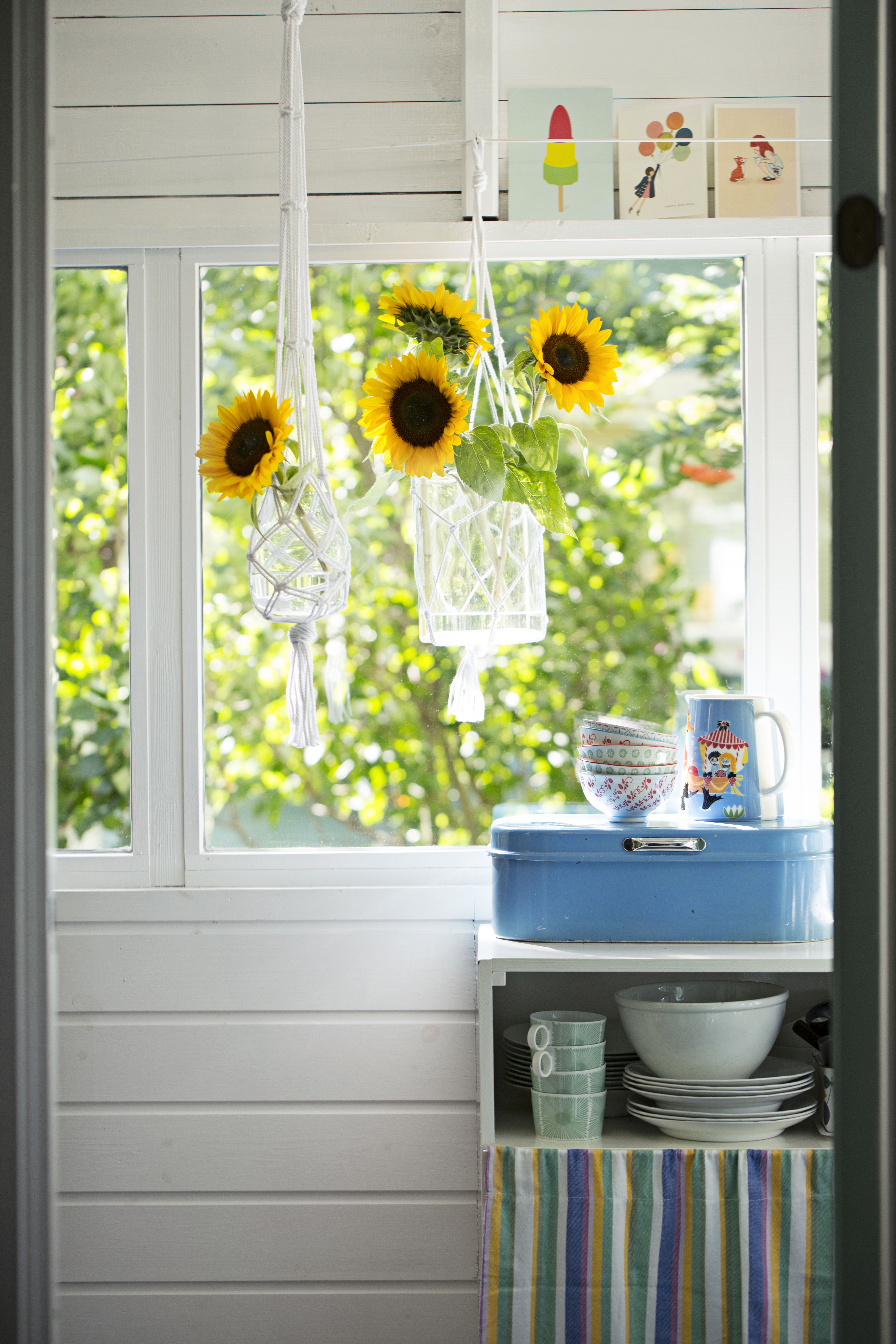 Kuistin kaunein amppeli on solmittu kierrätyskuidusta tehdystä Moppari-puuvillalangasta. Pieni maljakko Muuto, Formwerk. Isompi maljakko Olkkari. Kulhot ja muumikannu Stockmann. Kortit Papershop. Lanka Menita. Kuva Anna Huovinen.