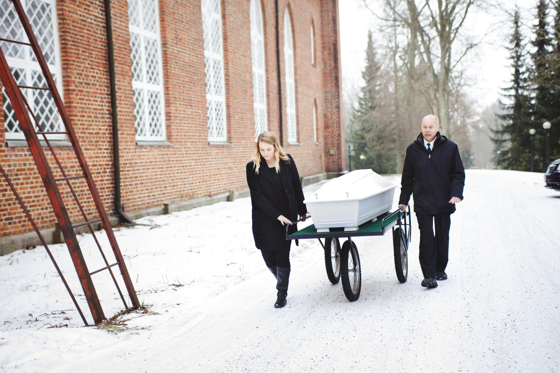 Isä Jari Prami auttaa siirtämään arkun kirkkoon ennen siunaustilaisuuden alkua.