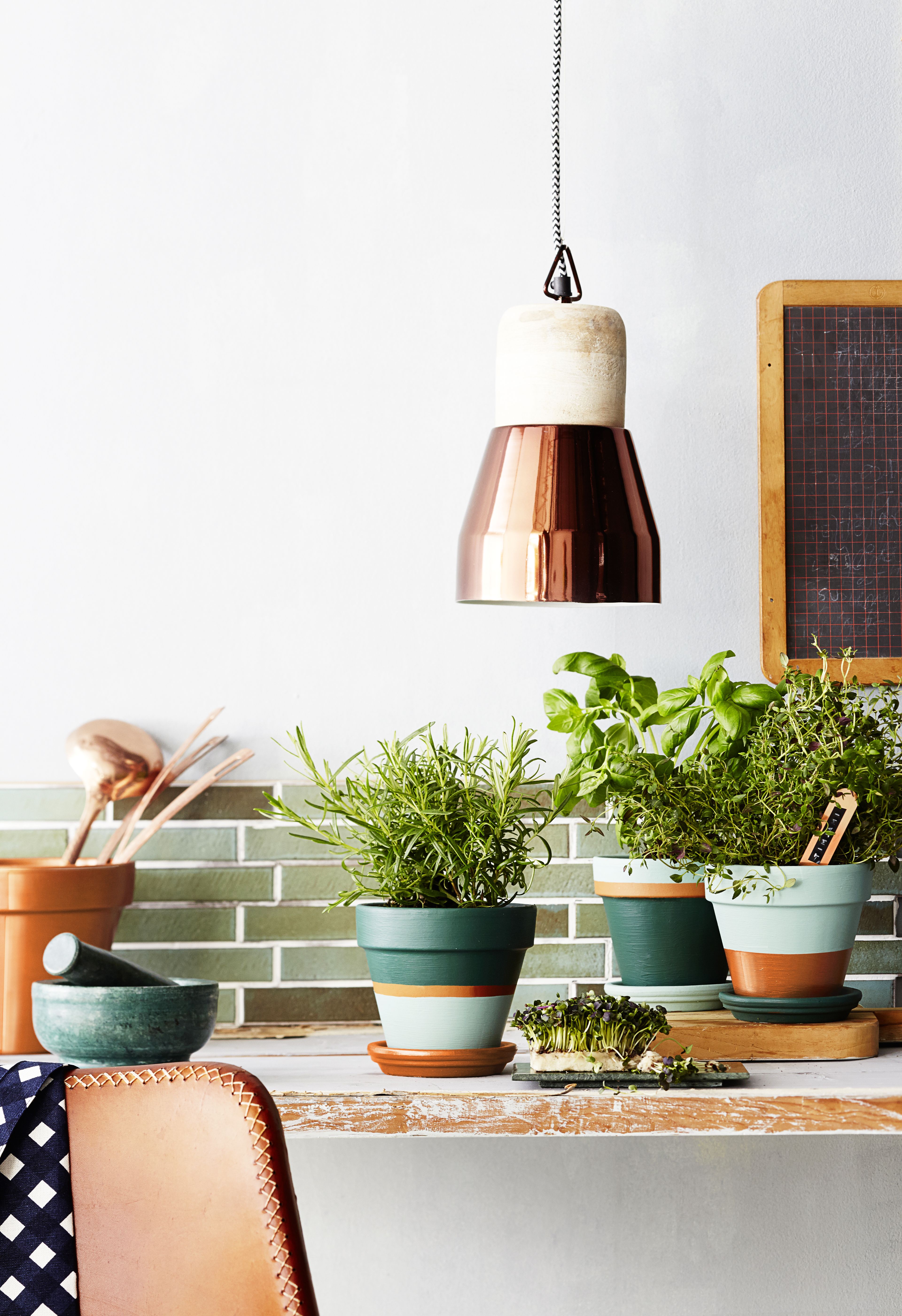 Ruukkulampun saa kaupastakin: Plootun kuparinvärinen Light & Living -valaisin maksaa 108 e. Kuvan muut esineet: Konjakinvärinen nahkatuoli 160 e, Plootu. Vihreä marmorimortteli 44,90 e ja kuparinen nimikyltti 6,90 e/10 kpl, Granit. Marimekon ruudullinen puoli-esiliina 47 e, Stockmann. Magna Antique Aquamarine -laatat 54,60 e /neliö, Kaakelikeskus. Muut tavarat kuvausrekvisiittaa.