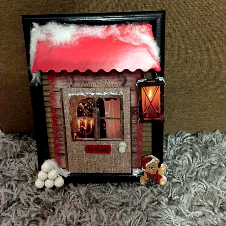 "Tein töihin tonttuoven:&nbsp;taulun kehys runkona, pahvista ja vanhoista joulukorteista leikkasin osia. Liimasin taakse pahvinpaloja, että se näyttäisi kolmiulotteiselta. Lyhty on tehty pienistä palloista, joista leikkasin rautalangat pois." Anne Koivisto