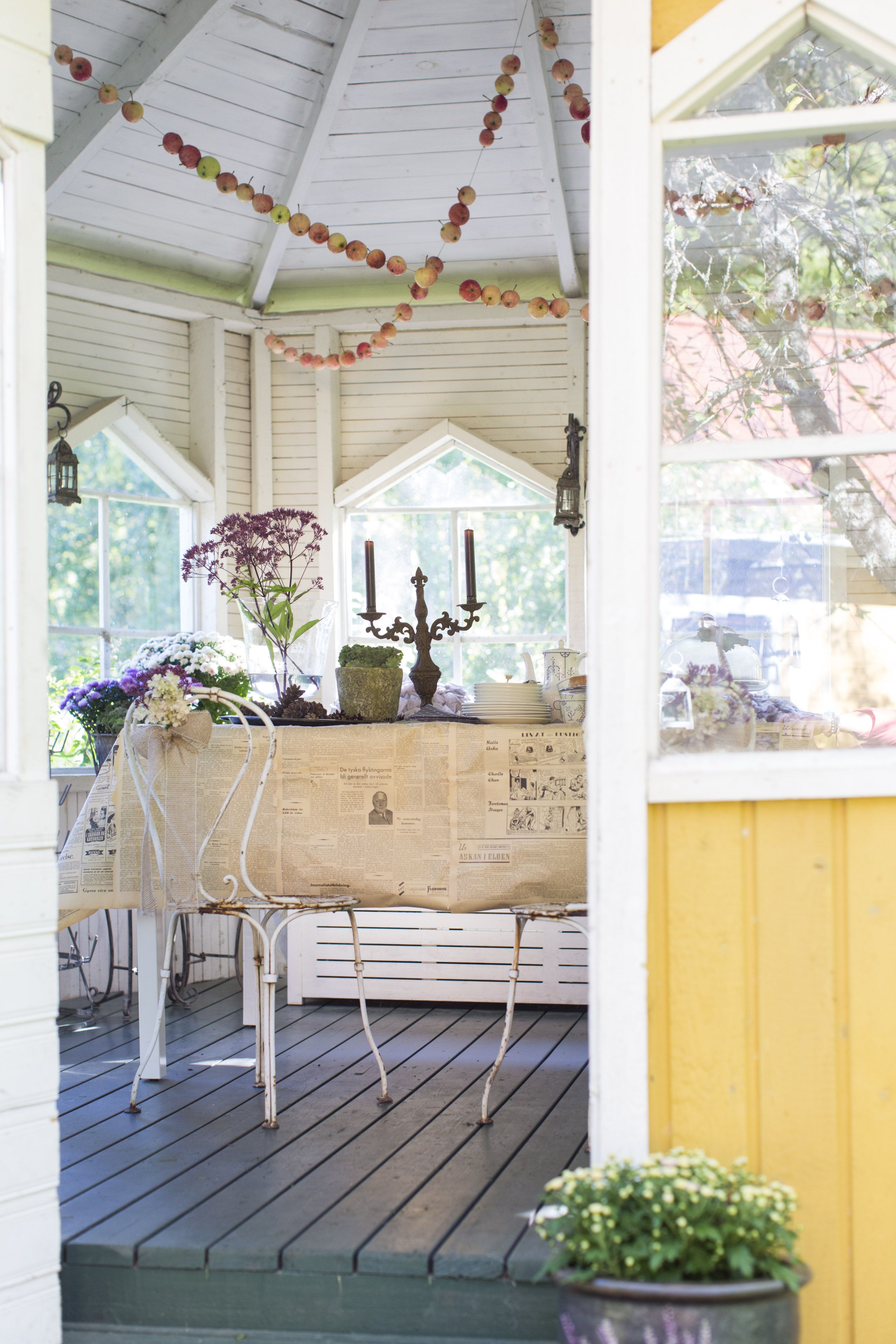 Keltaisessa huvimajassa vietetään aikaa varhaisesta keväästä pitkälle syksyyn. Kattoa koristavat Riikan tekemät omenaketjut.