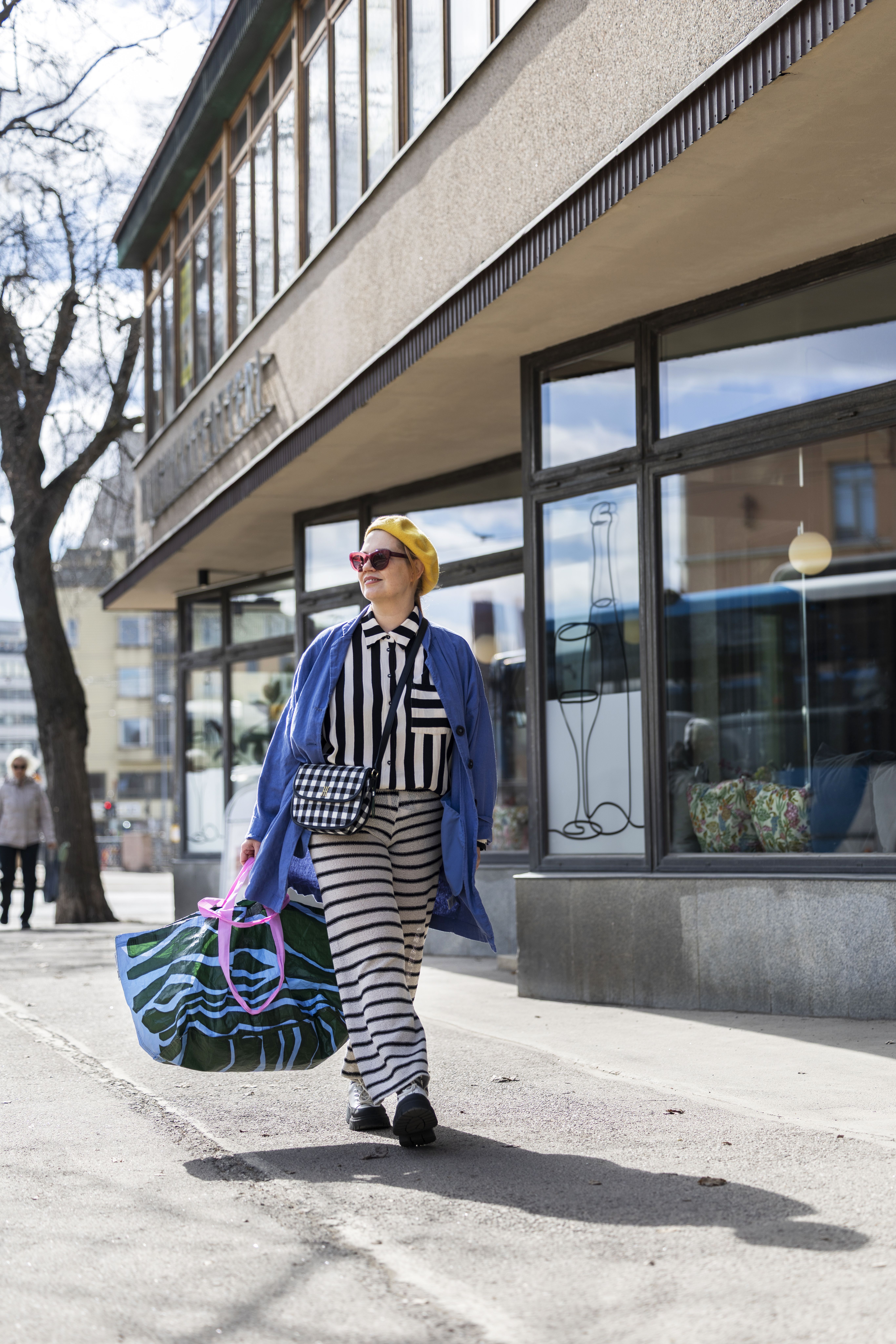 Raidoista tulee Sannalle hyvä olo. Päässä on yksi monista baskereista ja kädessä Ikea-kassi, jonka kuosi on Maija Louekarin.